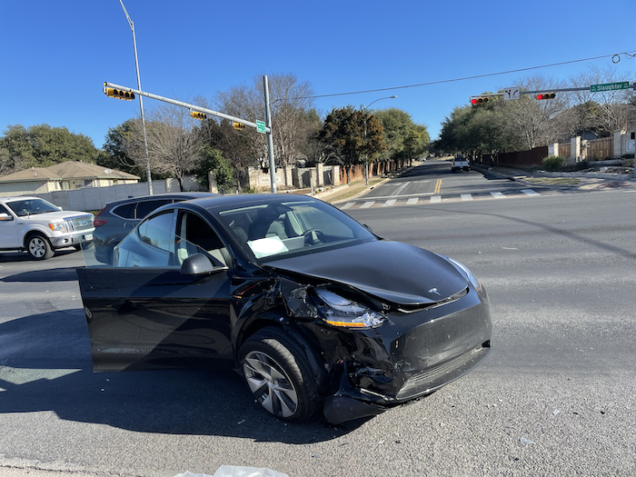 A black Tesla Model Y that is on the side of intersection after a collision.